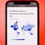 Picture of a smart phone displaying a map of coronavirus spread on screen